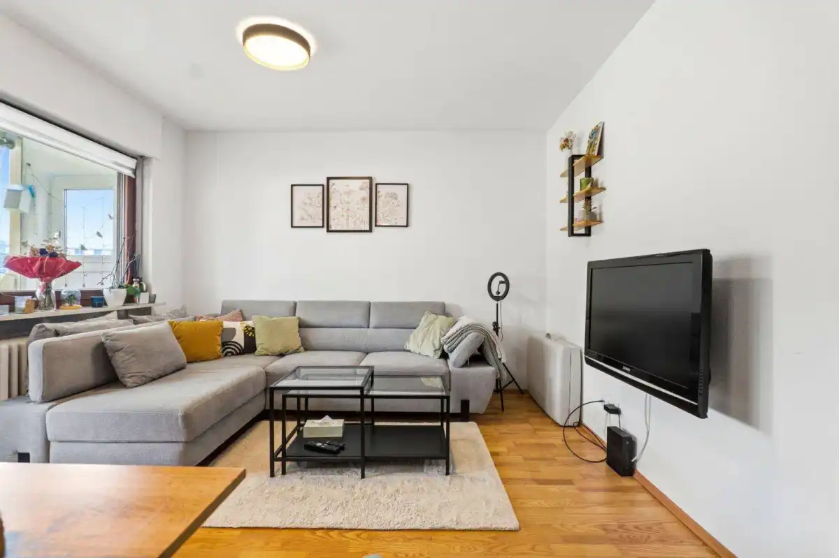 Gemütliches Wohnzimmer mit großem Ecksofa, Holzboden und moderner Einrichtung.