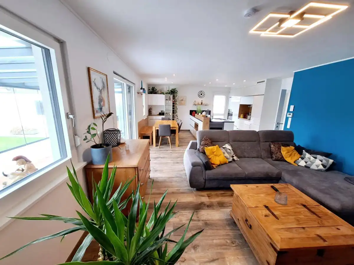 Heller offener Wohn- und Essbereich mit Holzboden, bequemer Couch und moderner Beleuchtung.