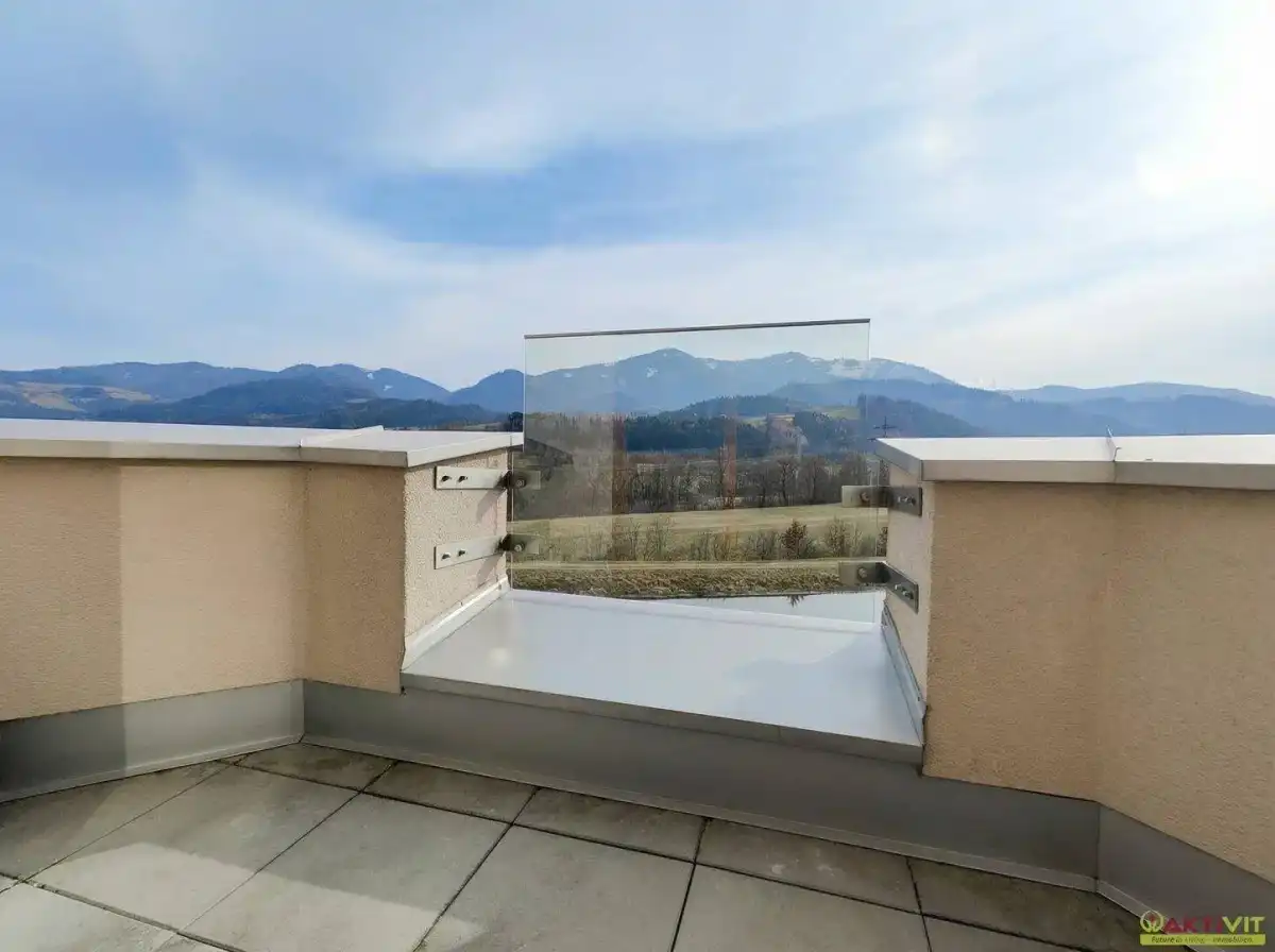 Geräumige Terrasse mit Glasbrüstung und weitem Blick auf die umliegende Berglandschaft.