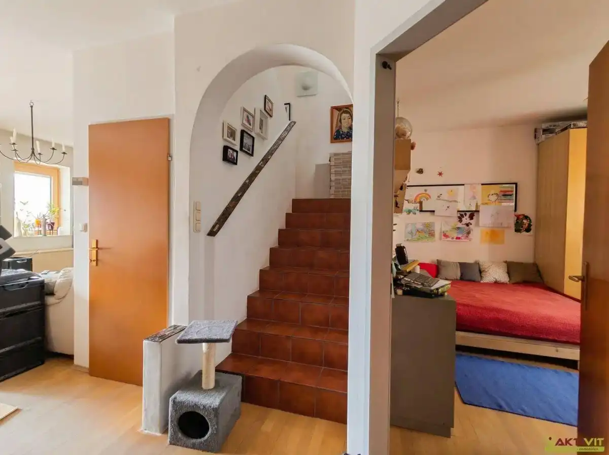 Heller Flur mit Holztreppe und Zugang zu einem Schlafzimmer.