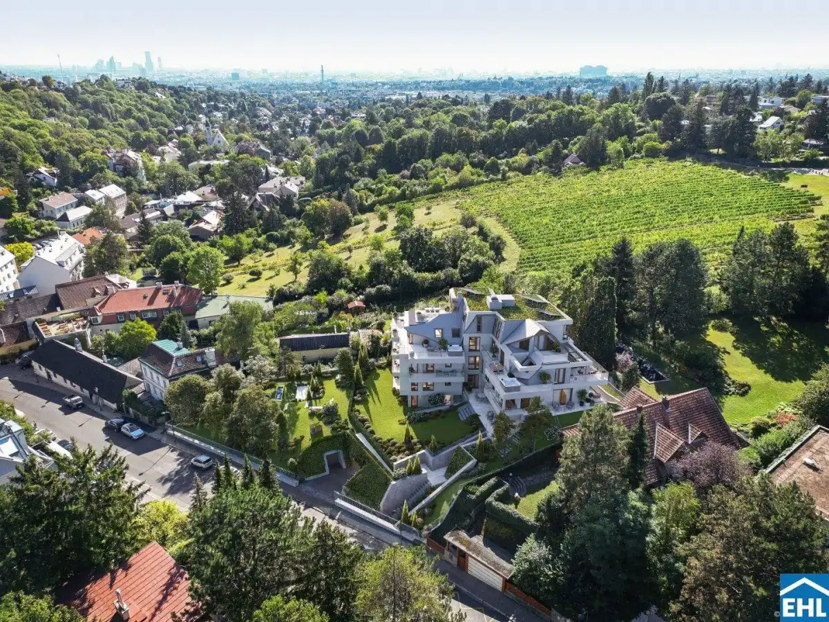 Luftaufnahme der modernen Wohnanlage in grüner Umgebung mit Blick auf die Stadt und Weinberge.