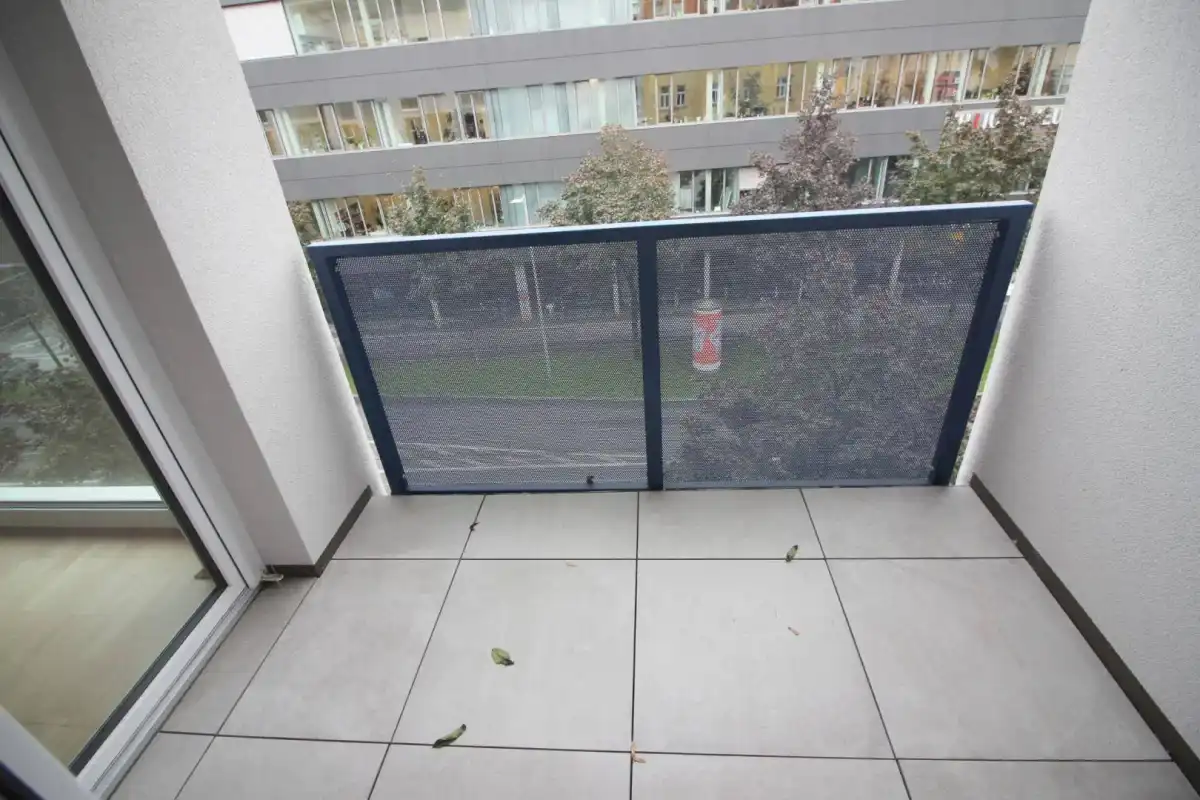 Kleiner Balkon mit Fliesenboden und Blick auf die Straße und umliegende Gebäude.