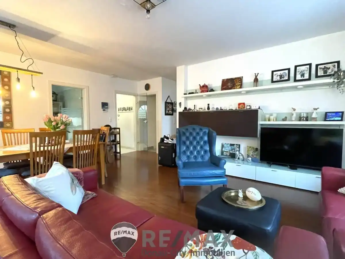 Heller Wohnbereich mit integriertem Essbereich, Holzboden und moderner TV-Wand.