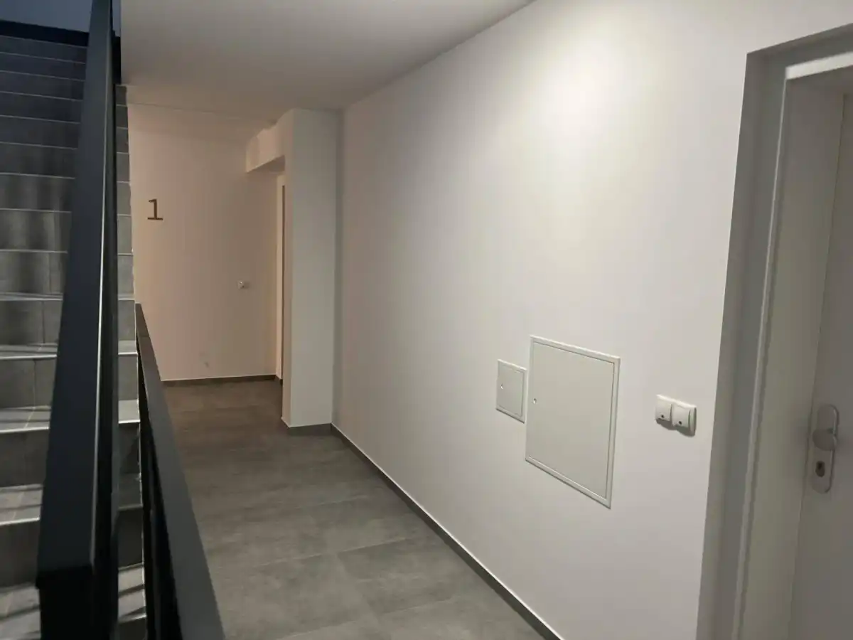 Heller Hausflur mit Treppenaufgang und Zugang zu den Wohneinheiten.