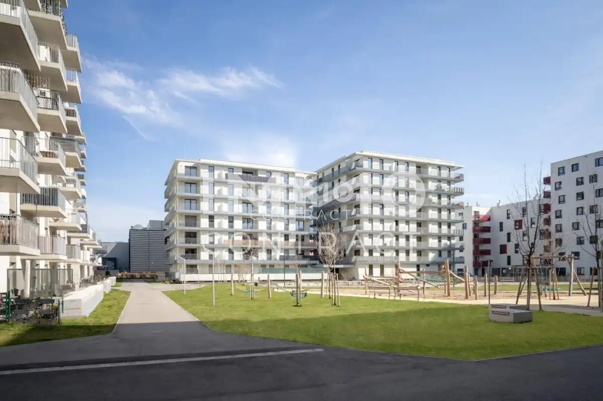 Wohnanlage mit modernen Gebäuden, Spielplatz und gepflegten Grünflächen.