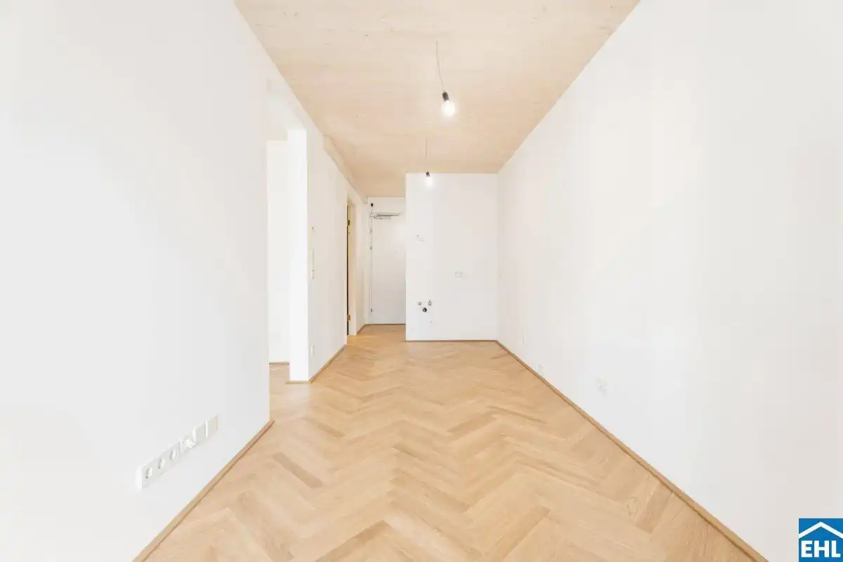 Geräumiges, helles Zimmer mit elegantem Fischgrätparkett und moderner Holzdecke.