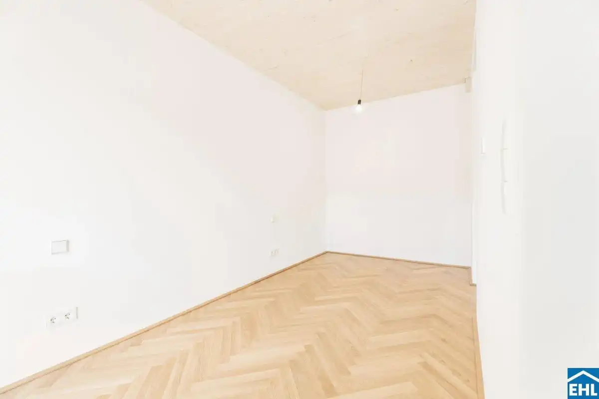 Heller, leerer Raum mit Fischgrätparkett und schlichter Holzdecke, ideal für flexible Nutzung.