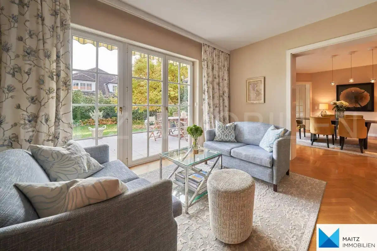 Gemütliches Wohnzimmer mit bequemen Sofas, Parkettboden und Blick in den Garten.