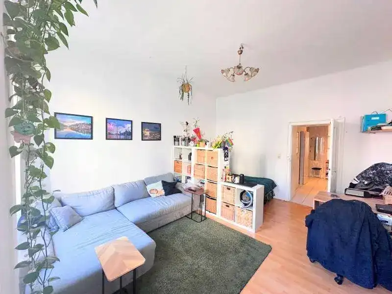 Gemütlicher Wohnbereich mit Ecksofa, Holzboden und Blick auf den Flur.