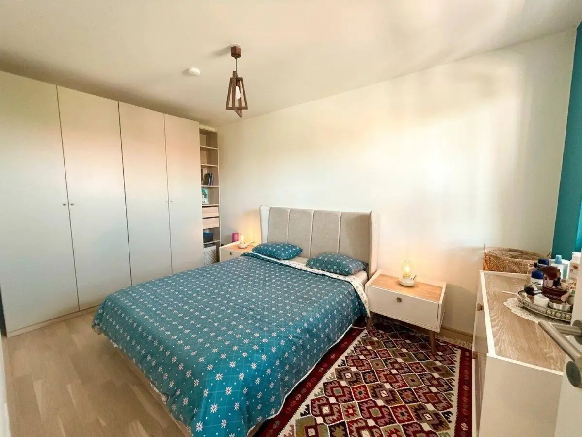 Helles Schlafzimmer mit Doppelbett, großem Kleiderschrank und Holzboden.