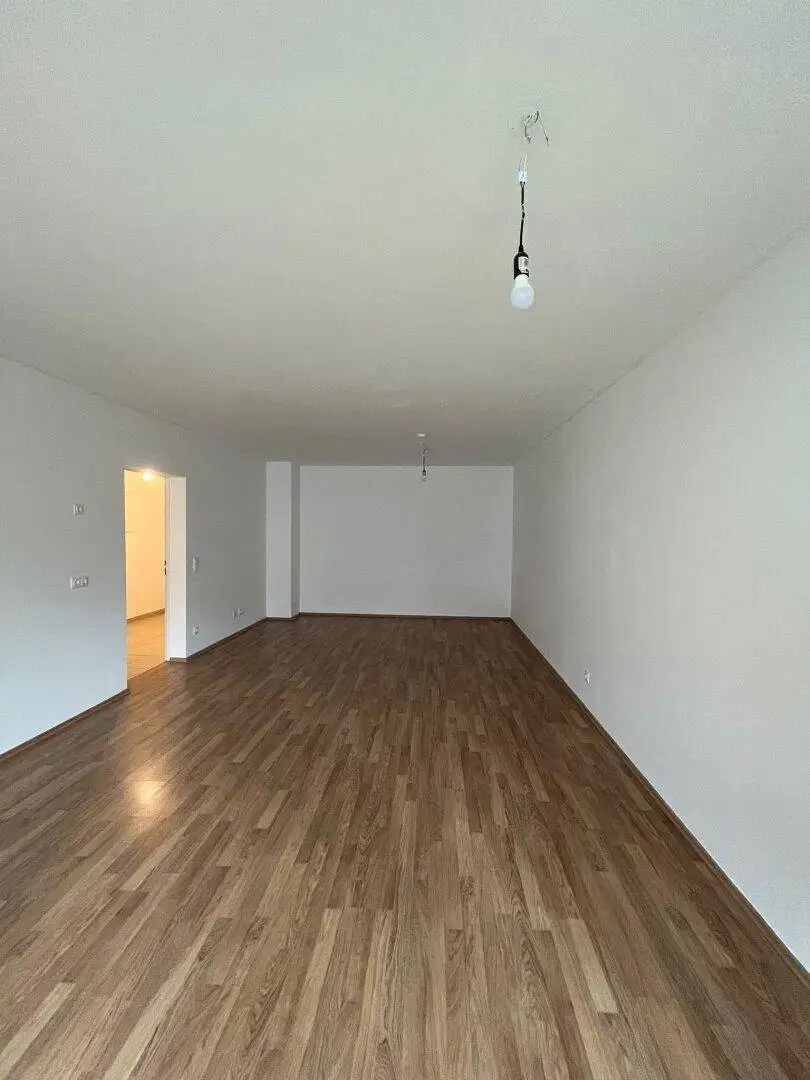 Geräumiges Wohnzimmer mit Laminatboden und hellen Wänden, bereit zur individuellen Gestaltung.