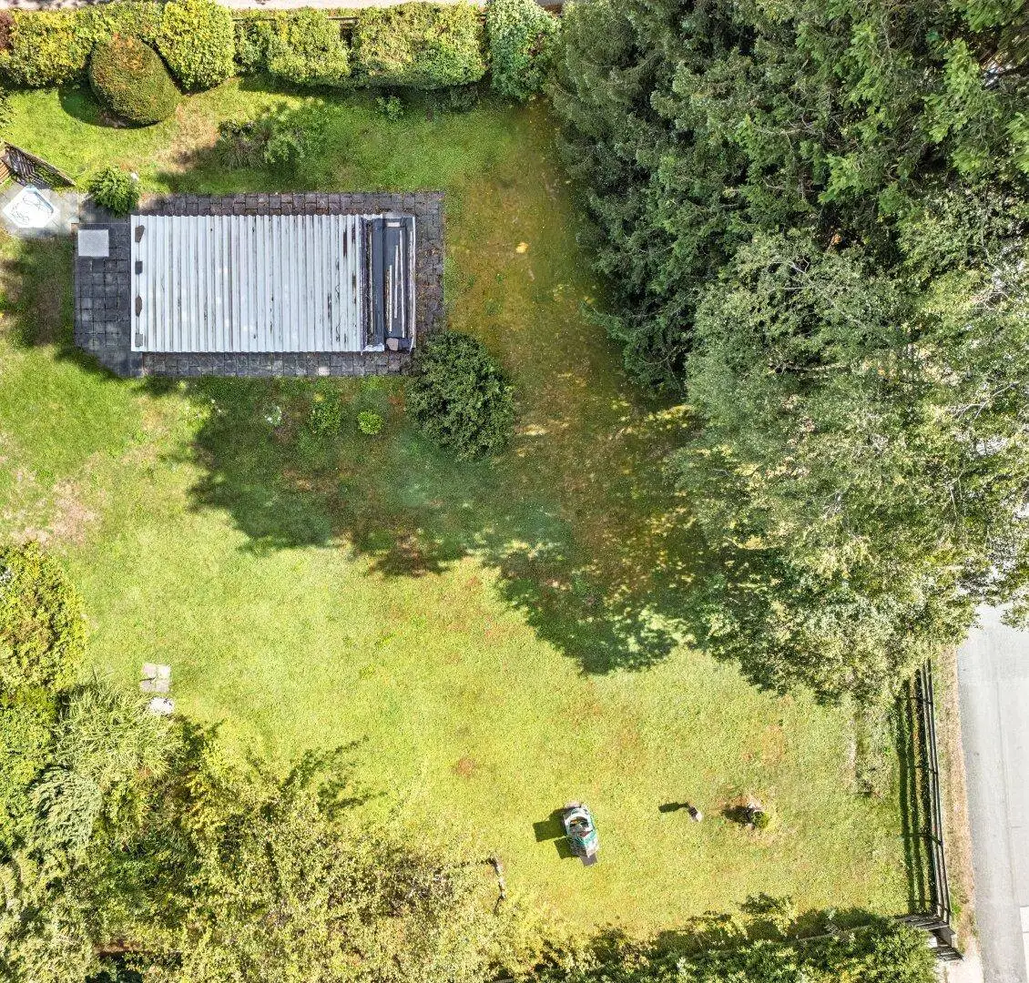 Luftaufnahme eines weitläufigen Gartens mit Rasenfläche, altem Baumbestand und einem Gartenhaus.