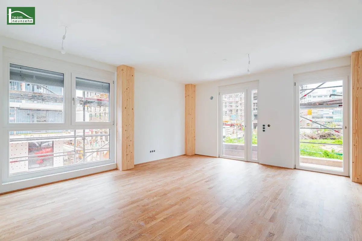 Geräumiger, heller Raum mit Holzboden und Zugang zu einem potenziellen Balkon oder Terrasse.