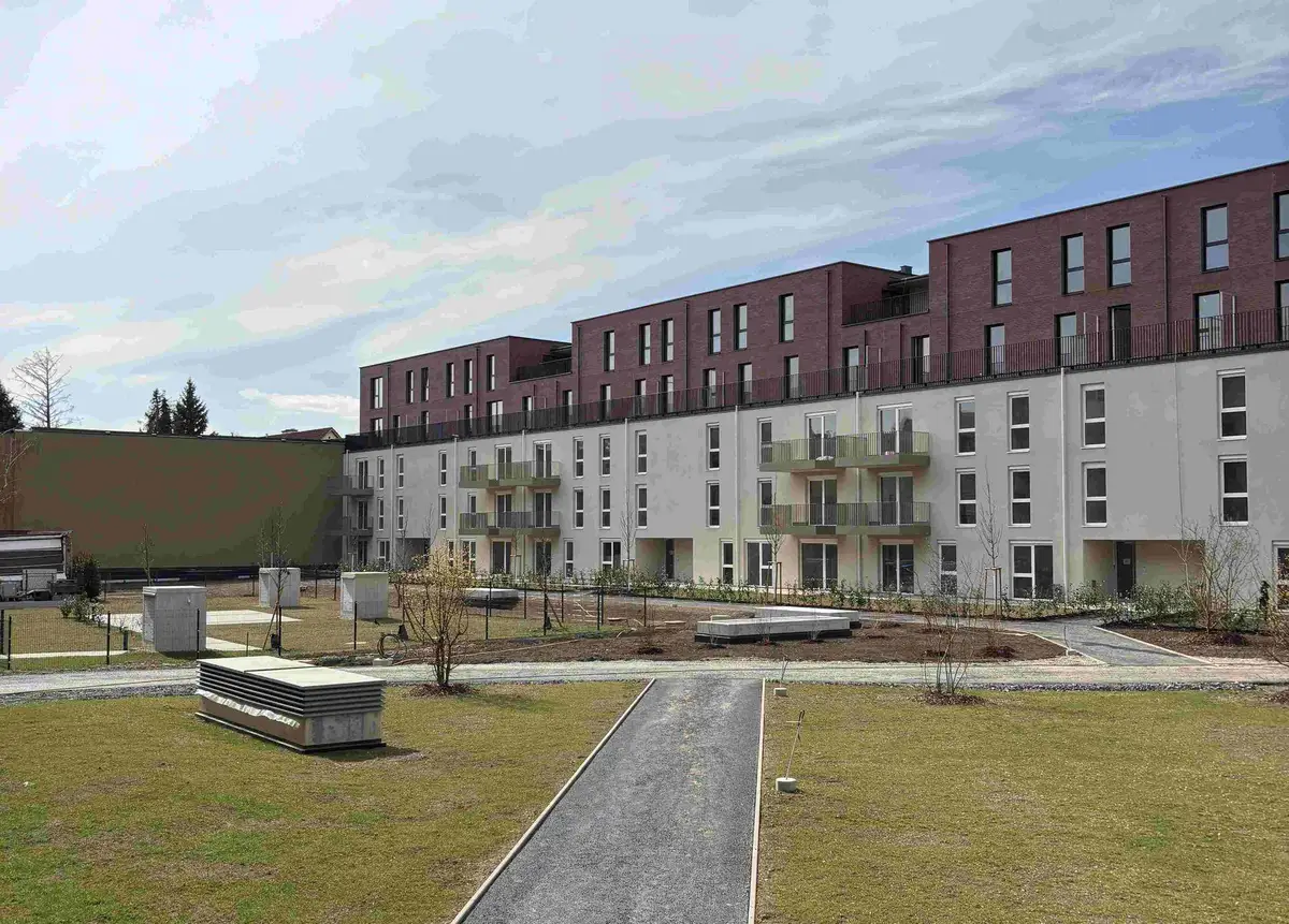 Neues Wohngebäude mit moderner Fassade und noch unfertigen Grünflächen im Außenbereich.