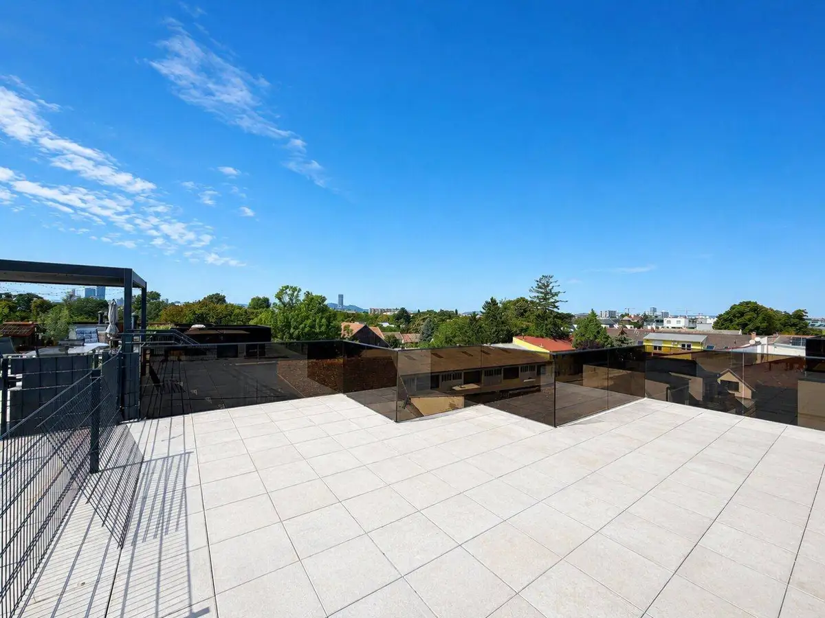 Helle Dachterrasse mit modernen Glasgeländern und weitem Blick über die Stadtlandschaft.
