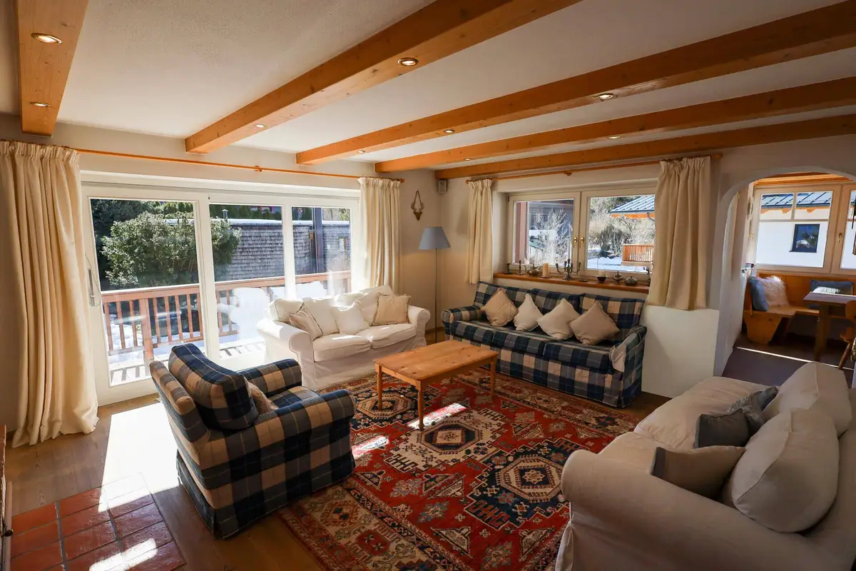 Helles Wohnzimmer mit traditionellem Teppich, bequemen Sofas und direktem Zugang zur Terrasse.