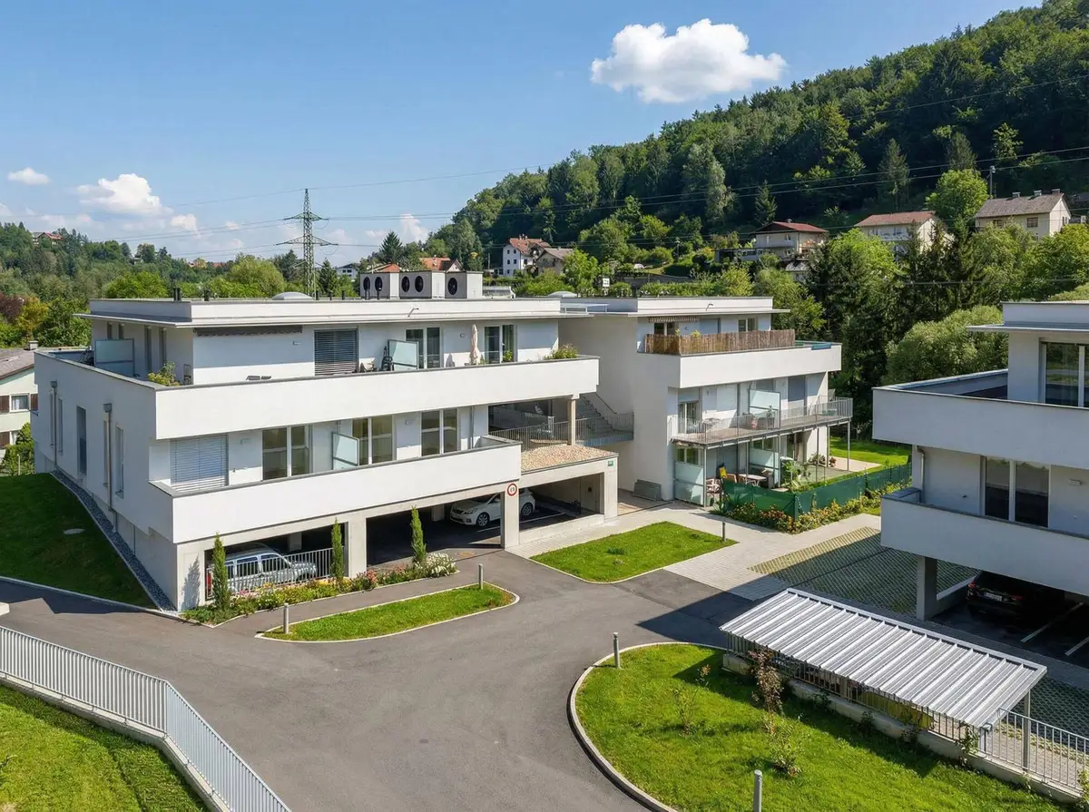 Überblick über die moderne Wohnanlage mit Tiefgarage, Carports und umgebender grüner Landschaft.