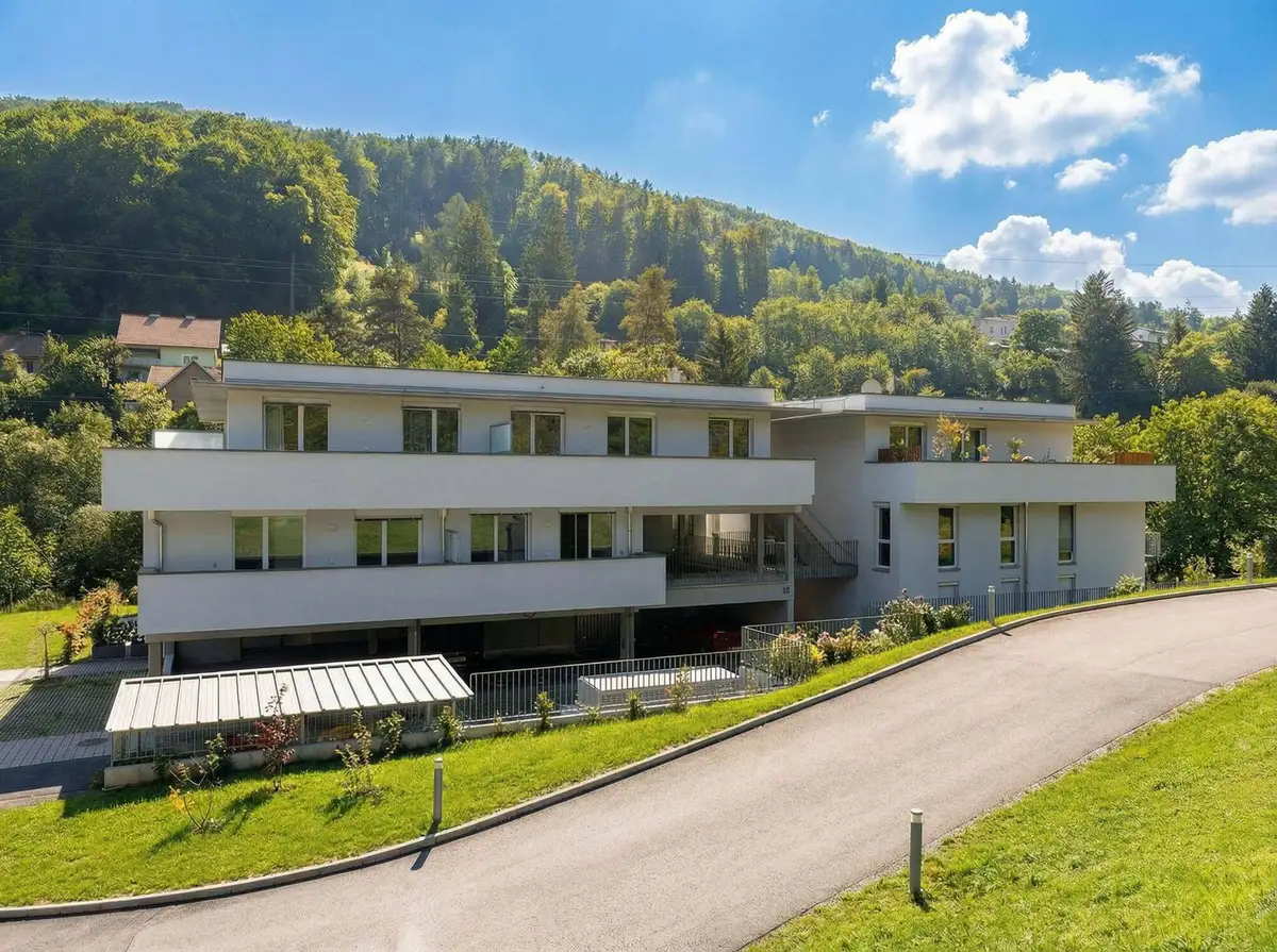 Weitläufige Ansicht der modernen Wohngebäude eingebettet in die hügelige, grüne Umgebung.