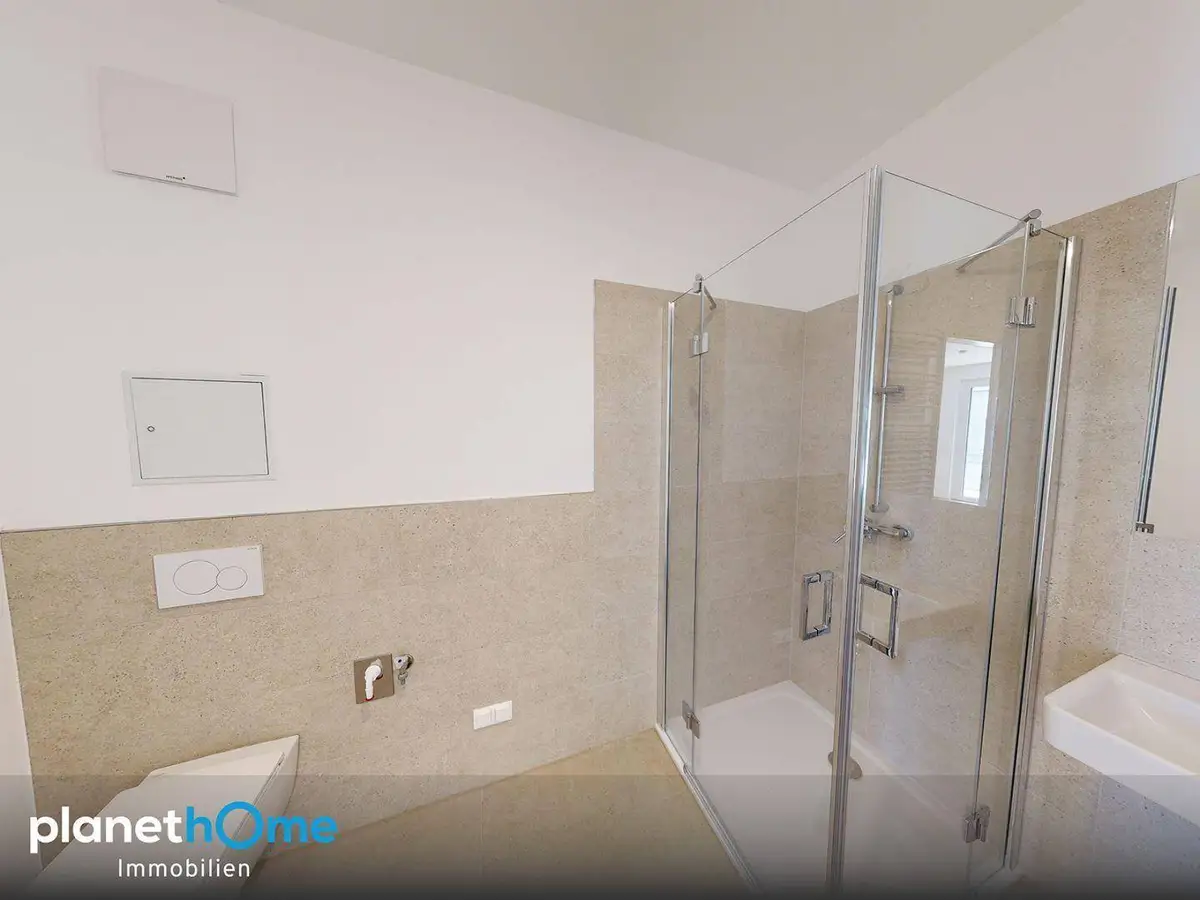 Modernes Badezimmer mit Duschkabine, Wand-WC und beigefarbenen Fliesen an Wänden und Boden.