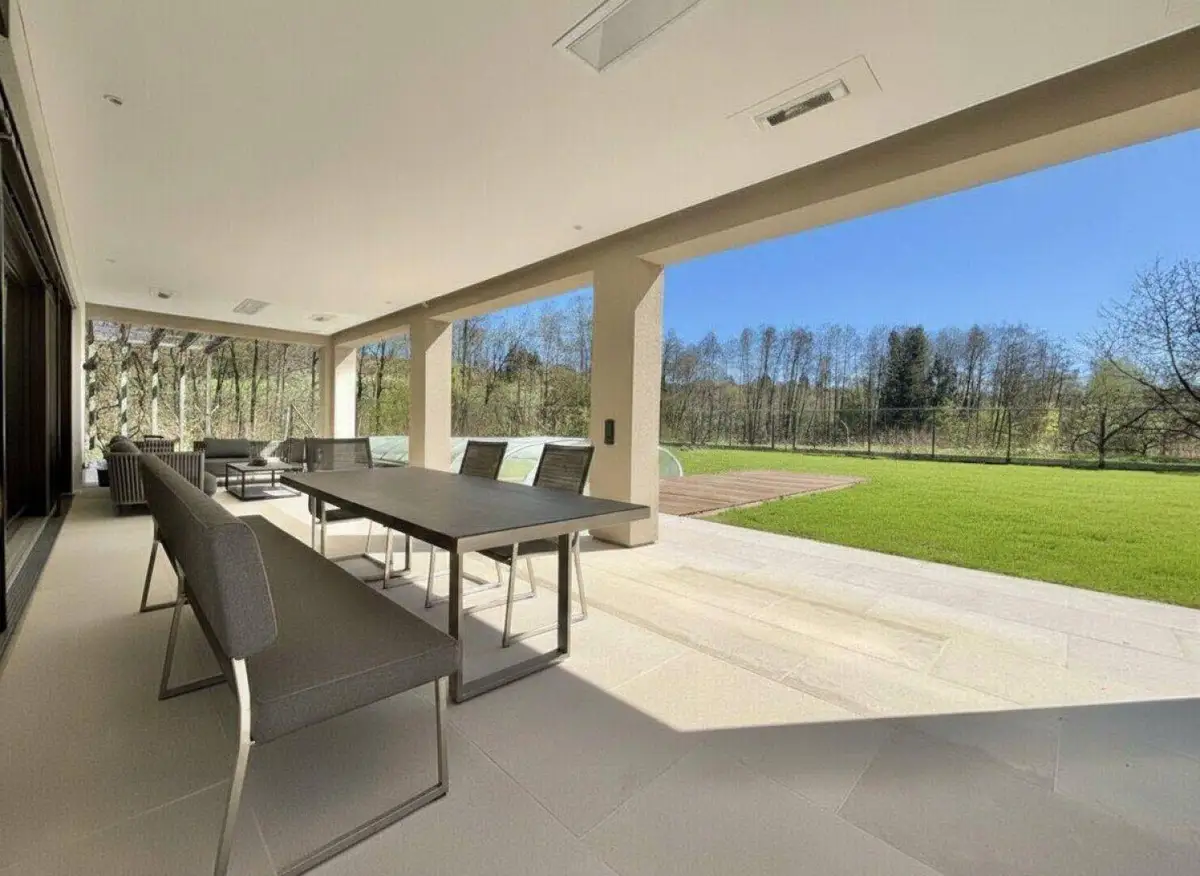 Überdachte Terrasse mit modernen Gartenmöbeln und Blick auf den weitläufigen Garten und die Natur.