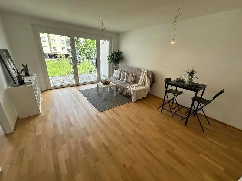 Heller Wohn- und Essbereich mit Parkettboden und Zugang zu einem Balkon.